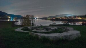 Steinspirale auf einer Wiese am Seeufer bei Nacht