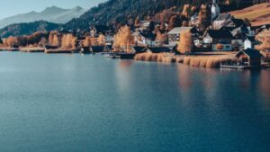Dorf mit Bootshütten am Seeufer im Herbst