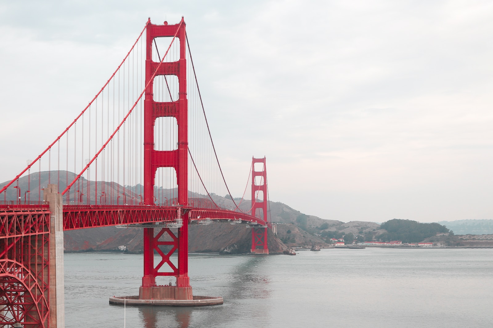 a red bridge over water with Golden Gate Bridge in the background