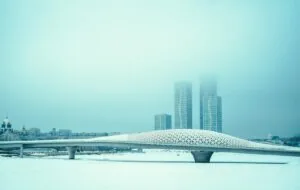 Moderne Wolkenkratzer und eine geschwungene Fußgängerbrücke in Astana im Winternebel